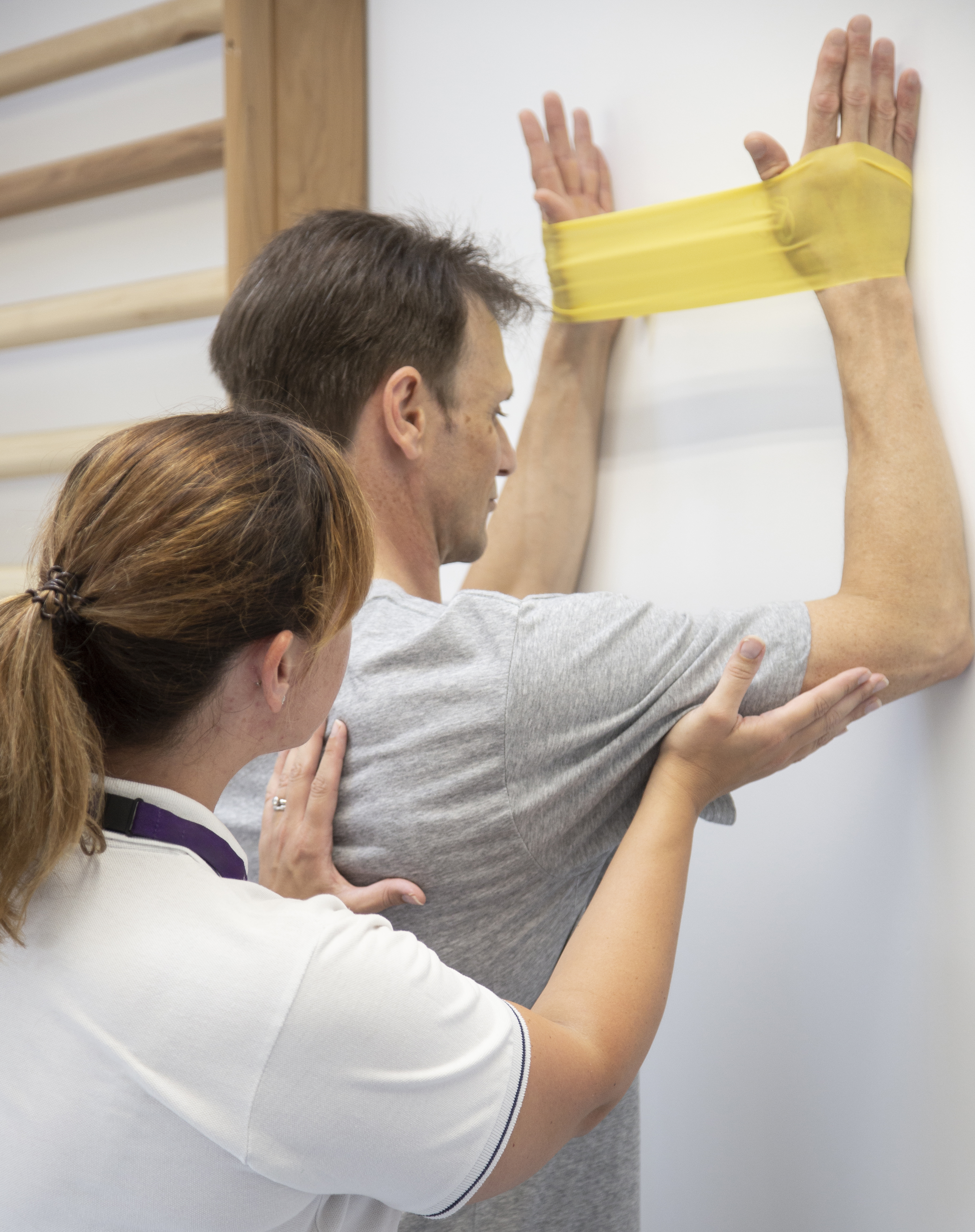 Physiotherapist assisting patient through elbow exercise using resistance band.