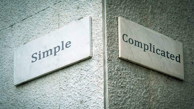 signs on a wall pointing in different directions saying Simple and complicated.
